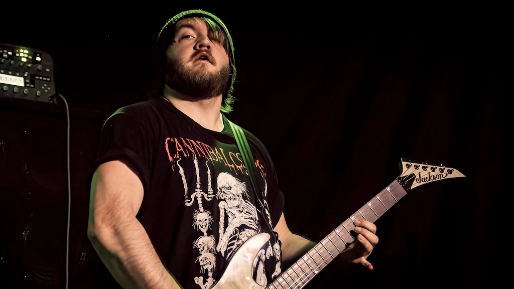 Chayse Burmeister audio engineer specializing in heavy music production, playing a guitar